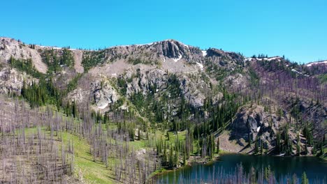 drone aerial shot pushing in over a backcountry backpacking lake past a rocky mountain range