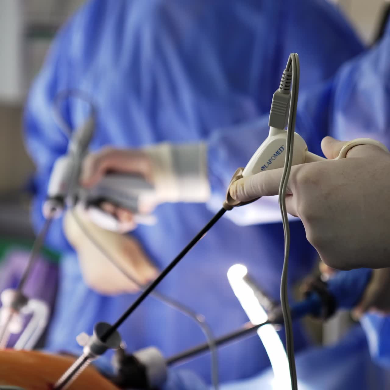 Both hands of a surgeon wearing latex gloves hold medical devices. Laparoscopy carried out at modern clinics
