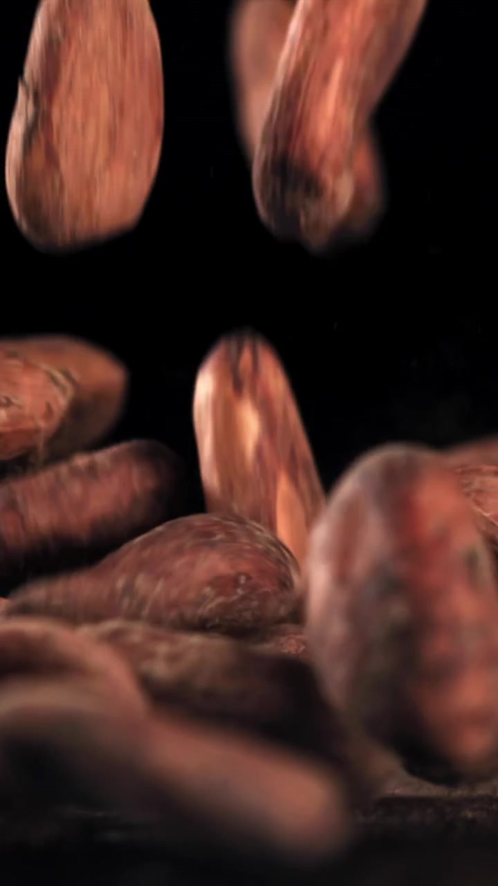 Granos de cacao crudos cayendo a cámara lenta sobre un fondo negro