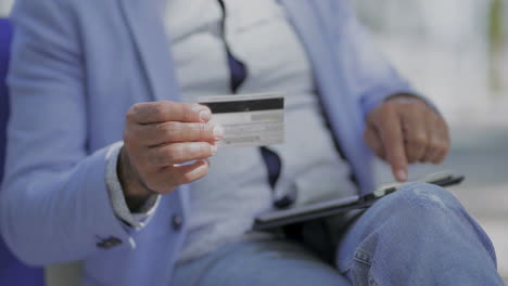 Man-holding-credit-card-and-using-tablet-pc