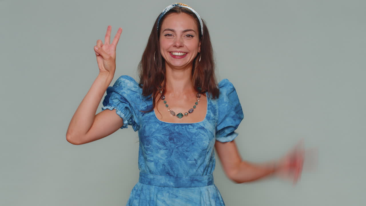 bella donna felice che mostra il segno della vittoria, sperando nel successo e nella vittoria, facendo un gesto di pace, sorridendo