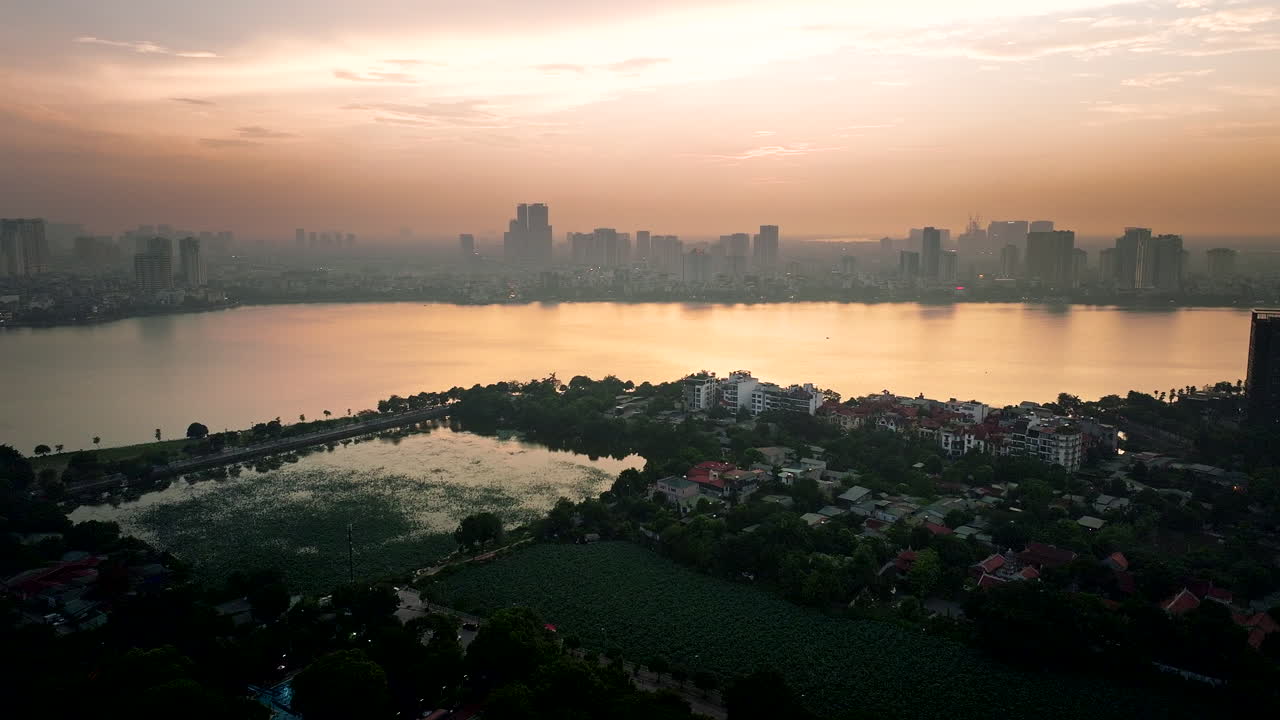 Hanoi Ho Tay lake with city skyline buildings at sunset under hazy sky due to climate change and air pollution, Panoramic aerial view