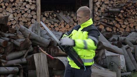 Lumberjack-in-reflective-jacket.-Man-woodcutter-with-electric-chainsaw.-Sawn-logs,-firewood,-sawmill