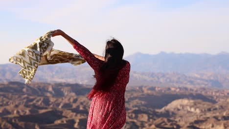 woman with scarf enjoying the wind in a mountainous landscape