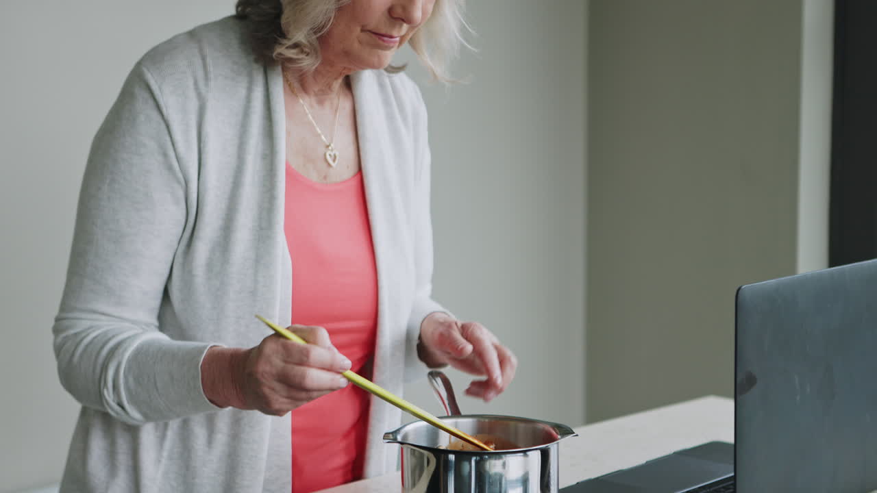 Woman Cooking and Using Laptop in the Kitchen