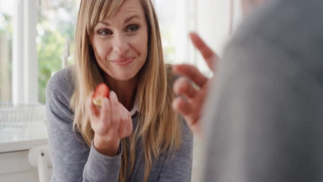 happy young couple eating breakfast together beautiful woman sitting with husband at table sharing morning meal in kitchen chatting with partner day in the life 4k footage