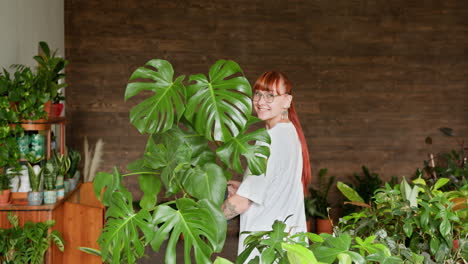 mujer rodeada de plantas monstera en una tienda de plantas