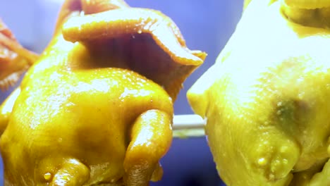 a detailed view of golden roasted chickens hanging in a bright display, showcasing their glossy texture.