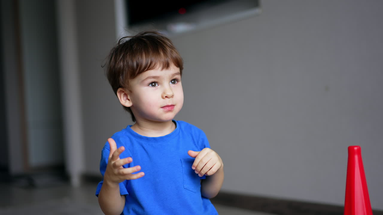 Little cute toddler playing cheerfully at home. Lovely baby puts the rings from pyramid on the head.