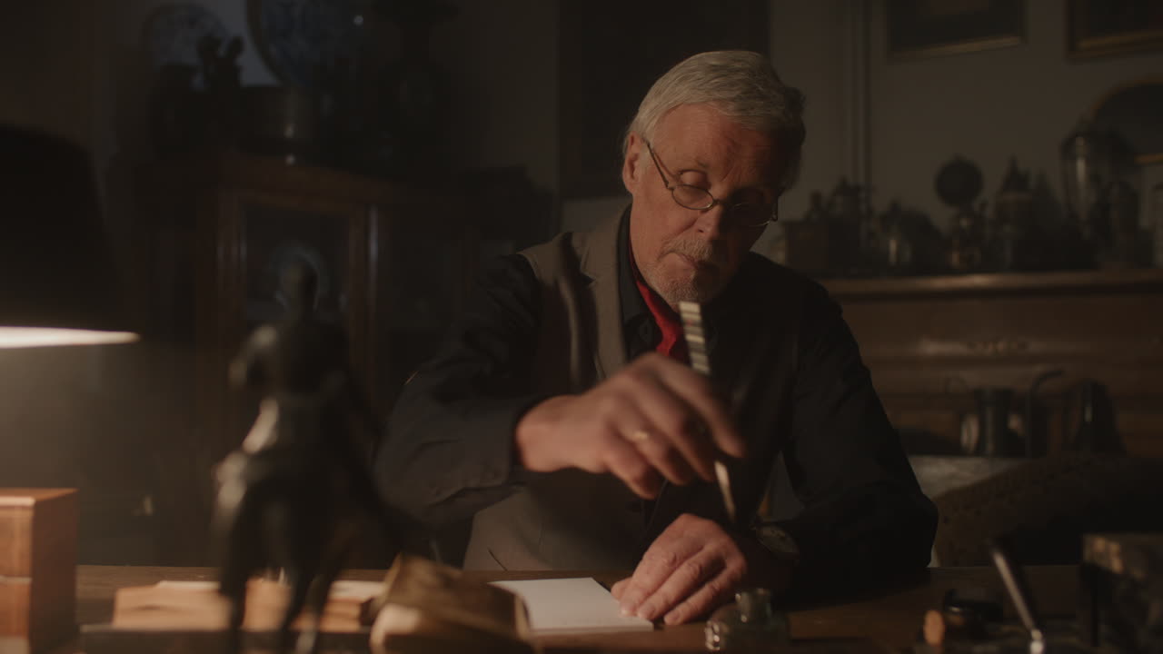 Old passionate man writes a letter in his office at night
