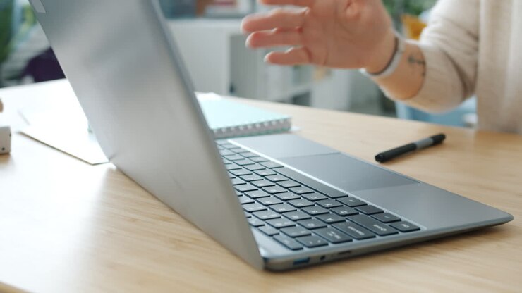 Donna che lavora al computer portatile e parla al telefono