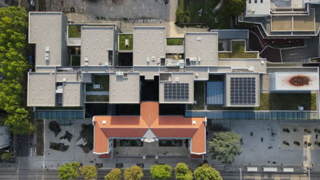 Toma-Aérea-Superior-Sobre-Un-Edificio-Moderno-Con-Un-Invernadero-De-Arte-Con-Paneles-Solares.