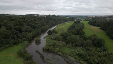 drone shot of a large river flowing through green fields in ireland