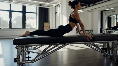 woman practicing a yoga or pilates pose on an exercise bench in a modern studio