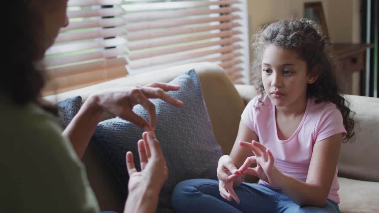 Happy mixed race mother and daughter playing with hands in living room