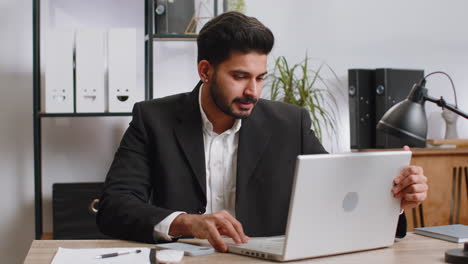 indian business man freelancer at office start working on laptop computer sends online messages