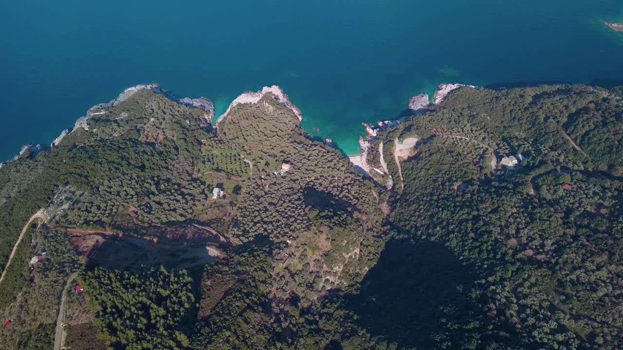 Inquadratura aerea dall'alto in avanti sulla costa con acqua cristallina.