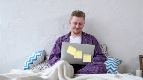 man working from bed in pajamas