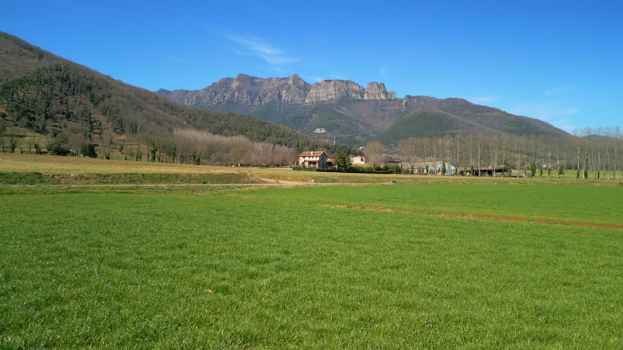 경작된 녹색 들판에 짐벌이 있고 배경에 전진하는 산이 있는 이미지