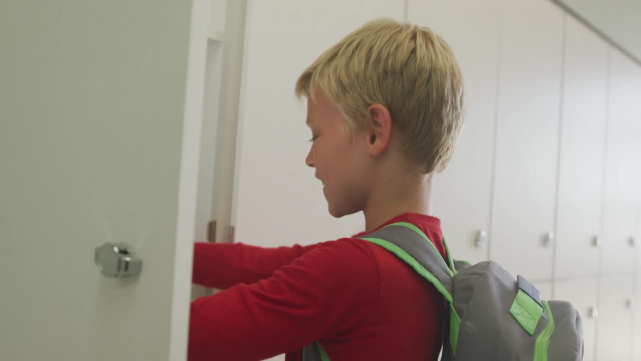 Video di un ragazzo caucasico che chiude l'armadietto e sorride a scuola.