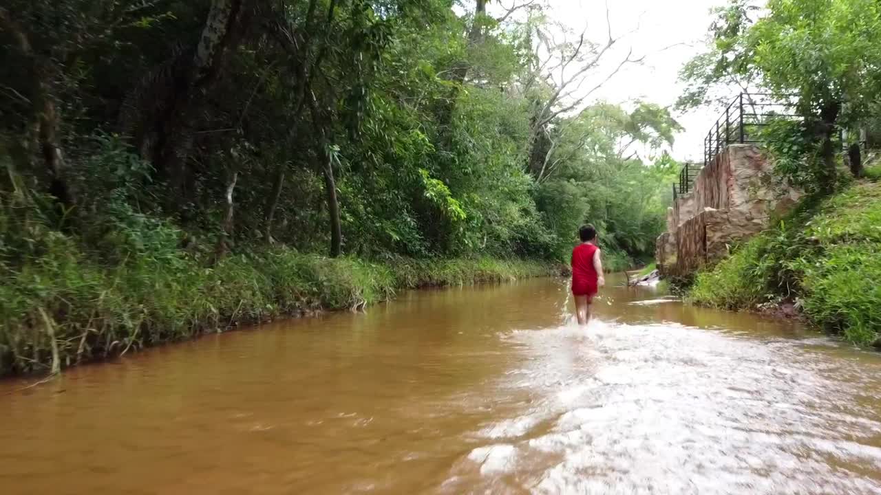 Menino correndo rio abaixo no Paraguai, América do Sul.