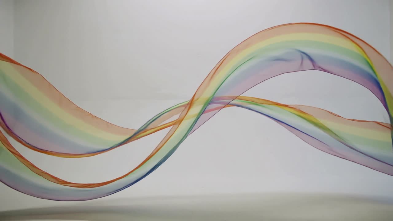 Translucent rainbow ribbons entering left sliding right looping crossing blending colors for design