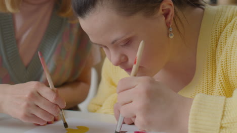 girl with down syndrome painting picture on art class