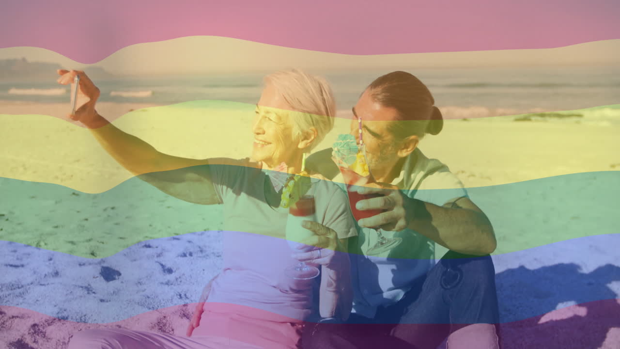 Taking selfie on beach, elderly couple with rainbow flag animation overlay