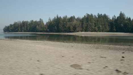 Volando-Sobre-La-Costa-Rocosa-Del-Parque-Estatal-Penrose-Con-Un-Exuberante-Bosque-De-Coníferas-En-La-Distancia-En-Lakebay,-Washington,-Estados-Unidos