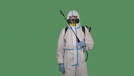 disinfection man with special white suite and a respirator sprays antiseptic solution on a green screen, chroma key. slow motion. close up