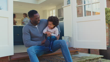 father and son sitting on step at home playing and having fun together