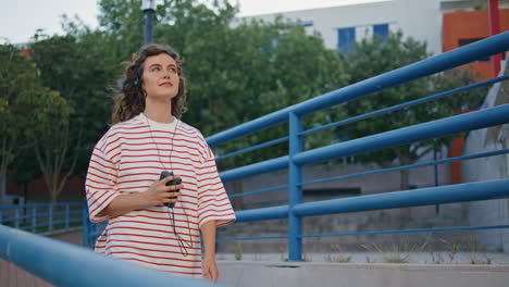 chica bonita caminando con auriculares en el fin de semana de verano urbano. mujer moviéndose con tacto