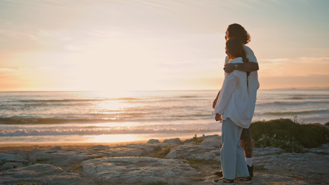 행복한 커플, 놀고 있는 개, 해가 지는 바다, 사랑하는 십대들이 모래 해변에서 안고 있다.