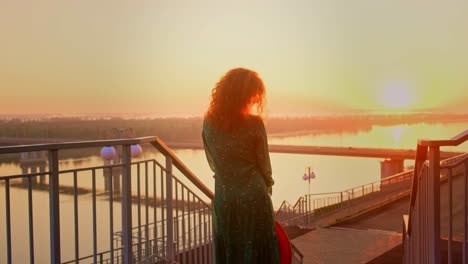 A Woman Silhouetted Against a Stunning Sunset Overlooking the River, Capturing the Serenity and Beauty of an Evening Stroll by the Water&#039;s Edge