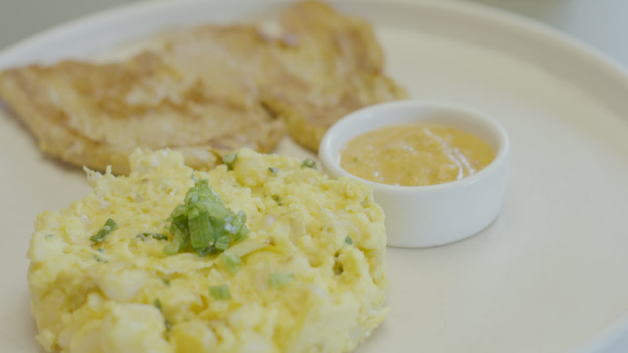 Close-up of a traditional dish that combines juicy roast meat, mote pillo prepared with mote, egg and finely chopped scallions, accompanied by artisanal chili sauce