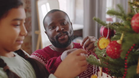 happy african american father and daughter decorating christmas tree at home