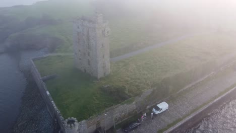 dron panorámico del castillo de carrigaholt y el puerto pesquero en una niebla marina a la deriva