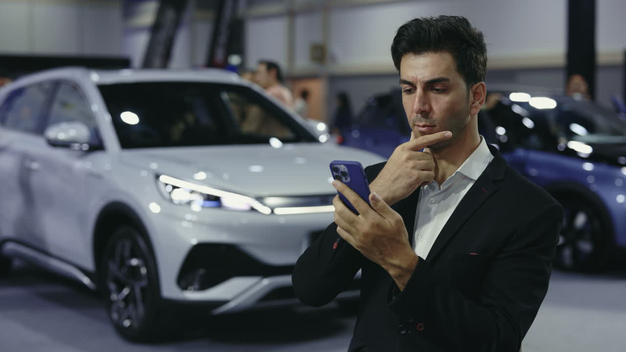 Businessman looking at phone at a car exhibition
