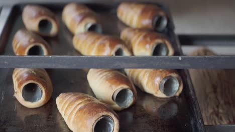 close-up of multiple trays filled with assorted baked pastries cooling on racks inside a bakery