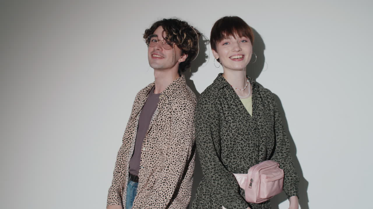 젊은 즐거운 커플이 스튜디오에서 쇼핑백과 함께 포즈를 취하고 있습니다.