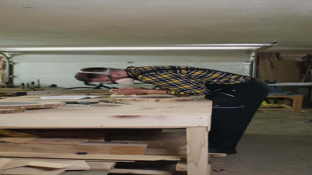 trabajador de la madera lijando losas de madera en el taller