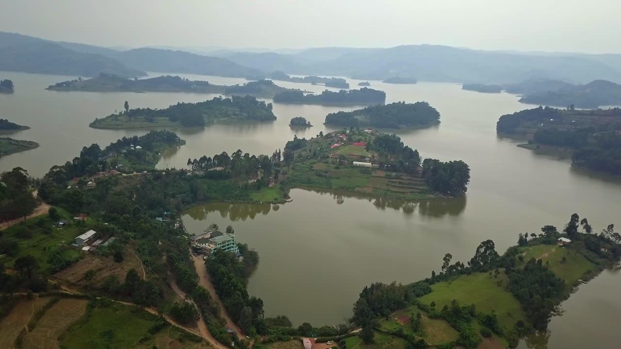 Drone aerial shot of Lake Bunyonyi in southwestern Uganda, showing its numerous small islands surrounded by rolling green hills, misty landscape create a peaceful African highland view
