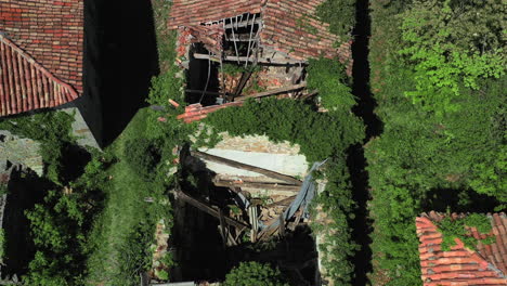 aerial top down view over overgrown abandoned building with broken roof tiles