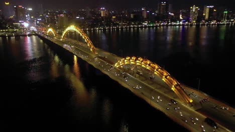 Amazing-colorful-aerial-of-iconic-Dragon-Bridge-Cau-Rong,-traffic-and-city-skyline-at-night-in-Danang,-Vietnam