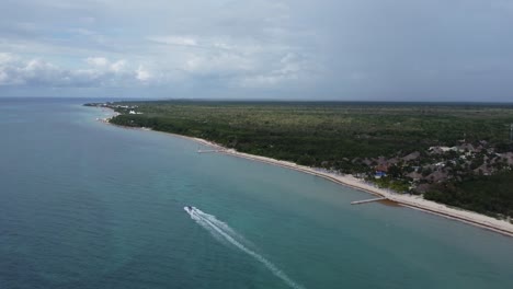 Ein-Boot,-Das-Entlang-Der-Küste-Von-Cozumel-Mit-üppigem-Grün-Rast,-Luftaufnahme