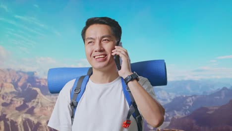 Close Up Of Asian Male Hiker With Mountaineering Backpack Smiling And Talking On Smartphone While Traveling At The Top Of Mountain