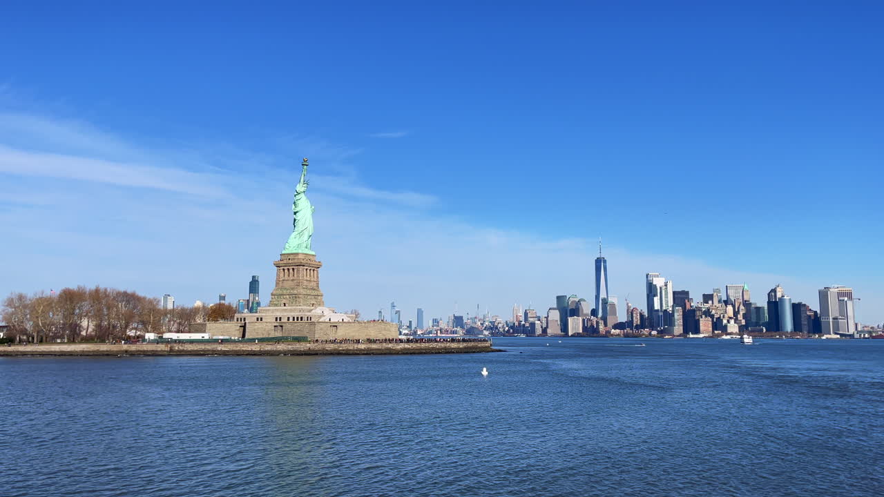 снимок с лодки статуи свободы с горизонтом нью-йорка на заднем плане в солнечный день