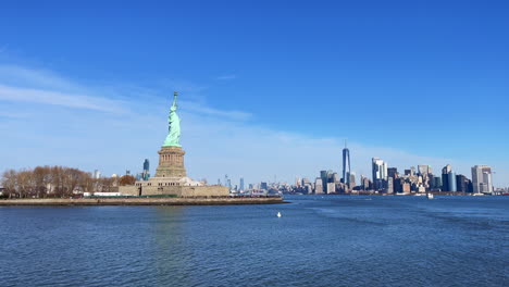 Shot-from-a-boat-of-statue-of-liberty-with-the-New-York-City-skyline-in-the-background-on-a-sunny-day