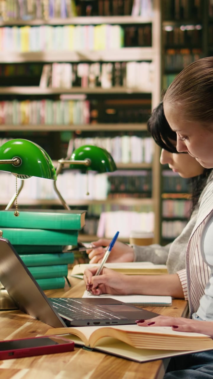 Video verticale Studente che scrive su un libro di testo e perde la concentrazione dopo aver ricevuto una notifica sul telefono