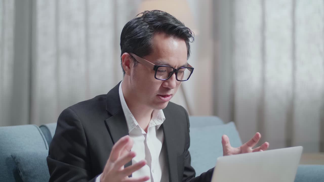 재과 쇼트를 입은 아시아 사업가가가 집에서 노트북으로 비디오 통화를 하고 있습니다.